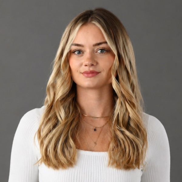 Woman with long blonde hair wearing a white top against a gray background